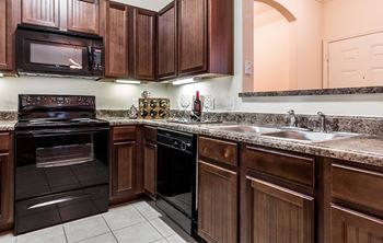 A kitchen with dark wood cabinets and black appliances.